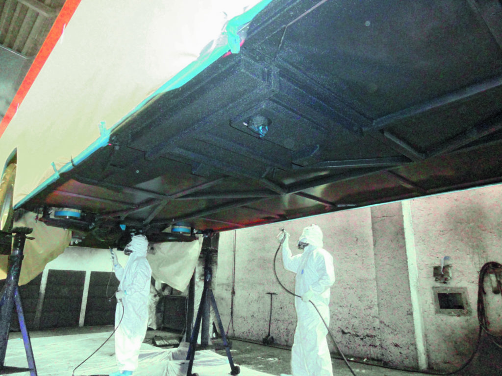 Image of protective coating being applied to underside of a train