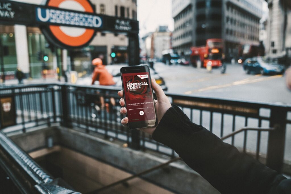 Someone holding a phone showing the Totalkare Podcast on Lifts and Pits