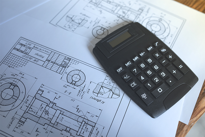 An image of a black calculator atop blueprint
