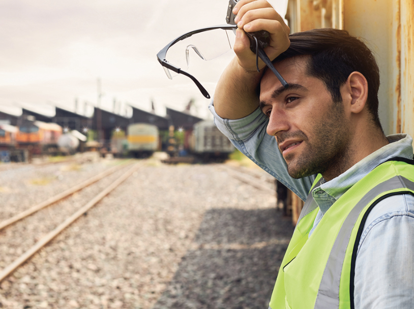 A worker on the tracks wiping the sweat from his forehead