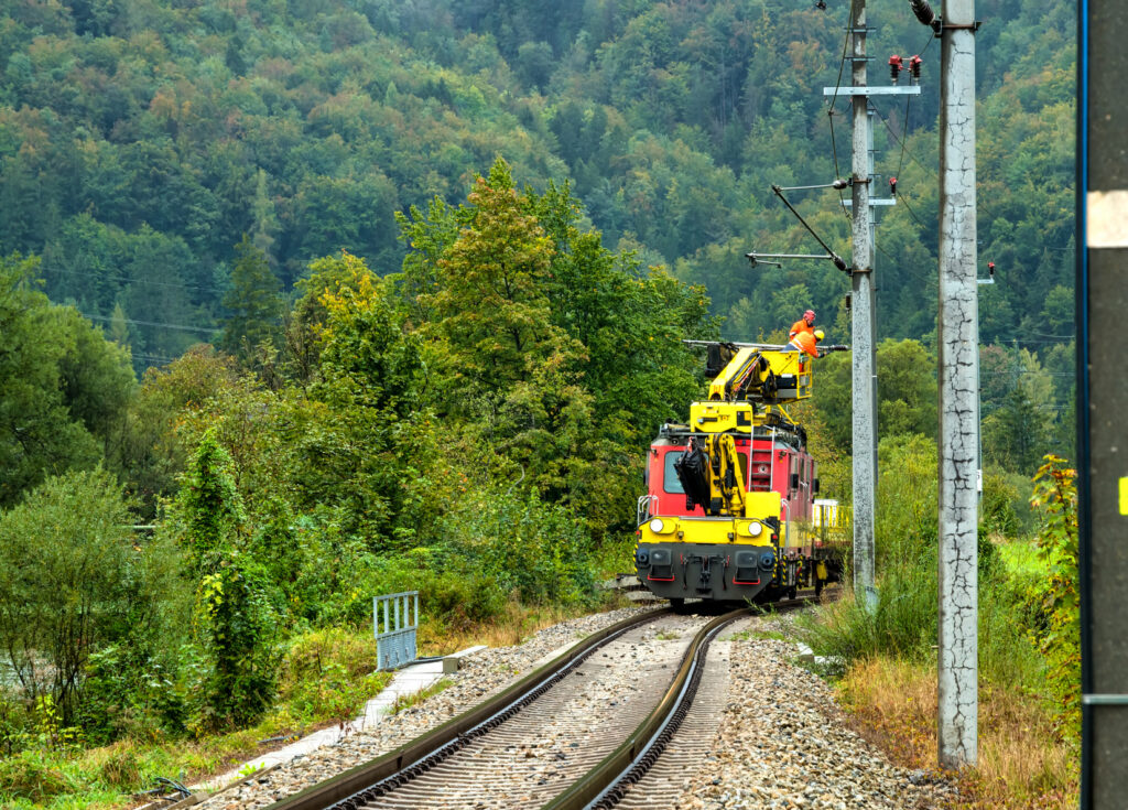 Work platform trolley with freely swivelling aerial work platform removes overhead line on the railway line