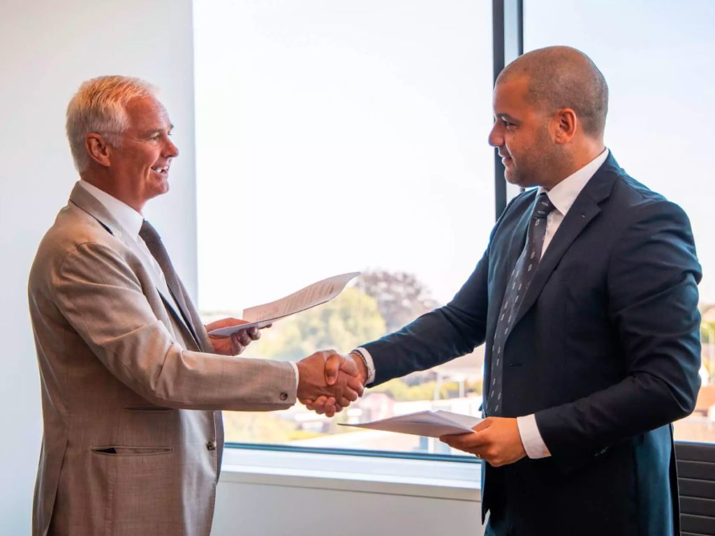 Two men in suits shake hands