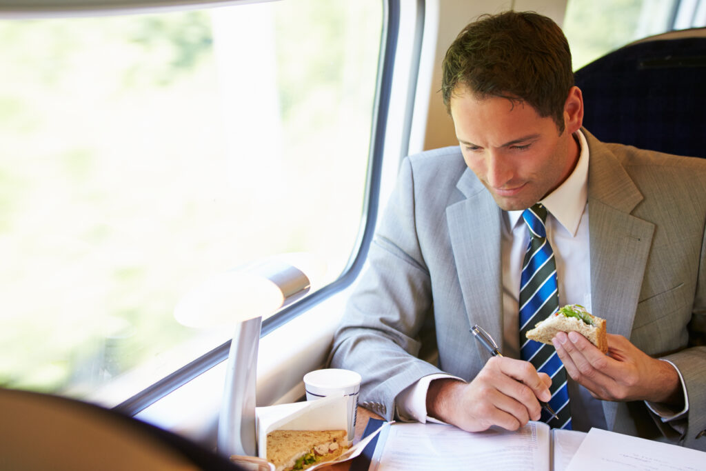 Businessman Eating Sandwich On Train Journey and working