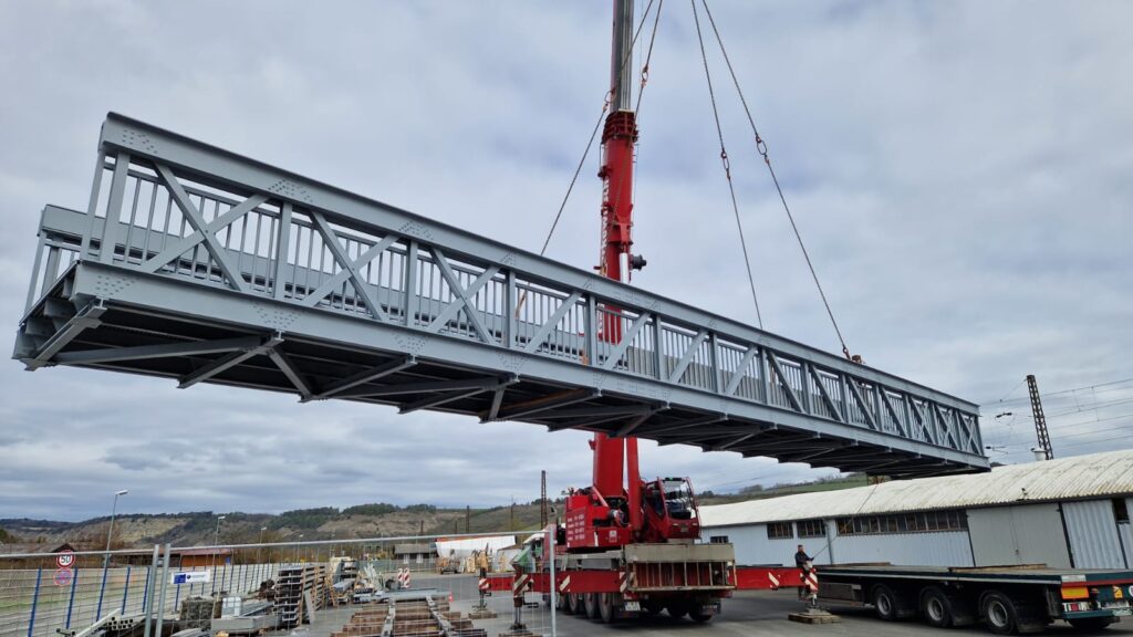 An image showing a bridge suspended via a crane