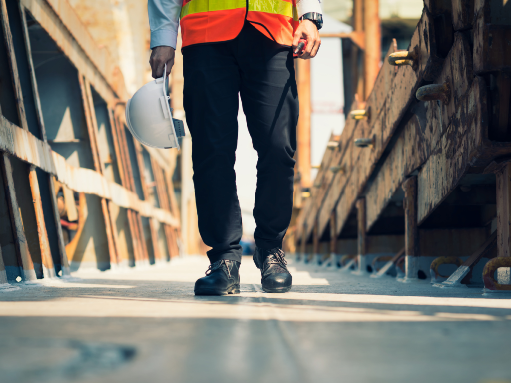 a worker in high vis walking across a bridge