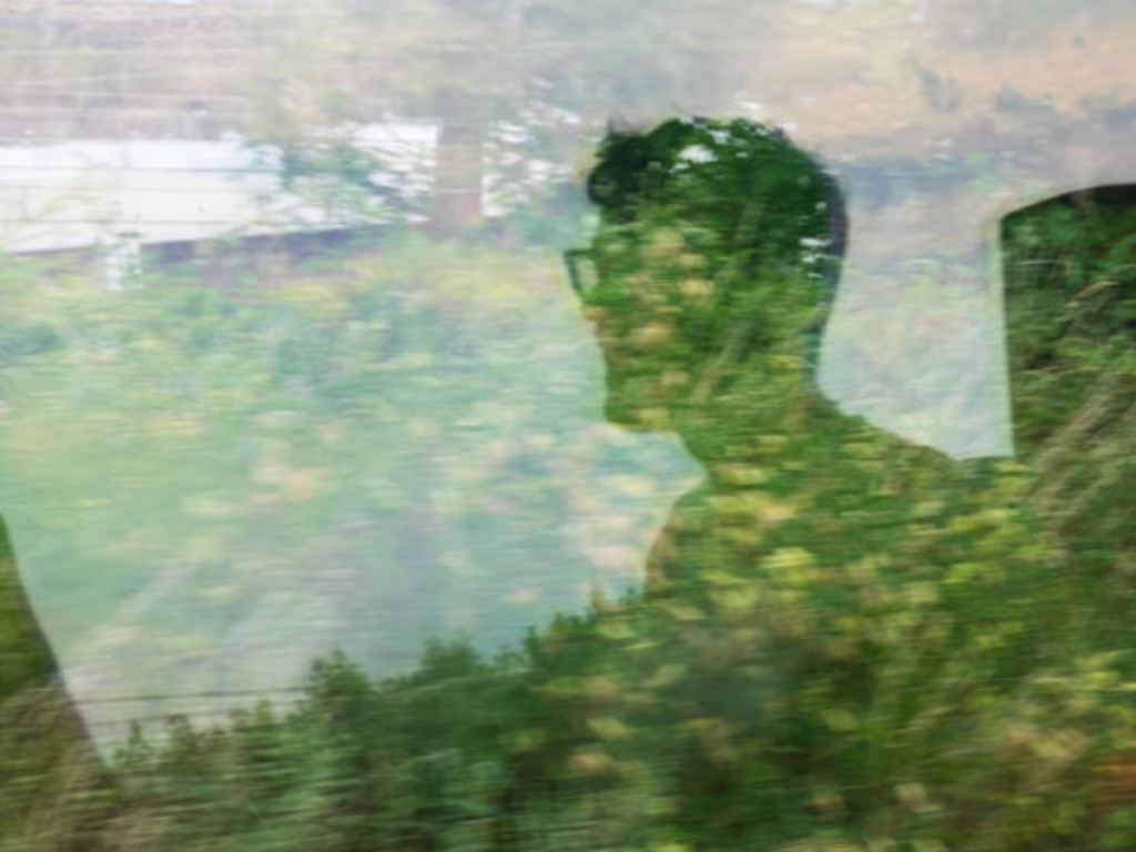 An image of a man's reflection in a train window