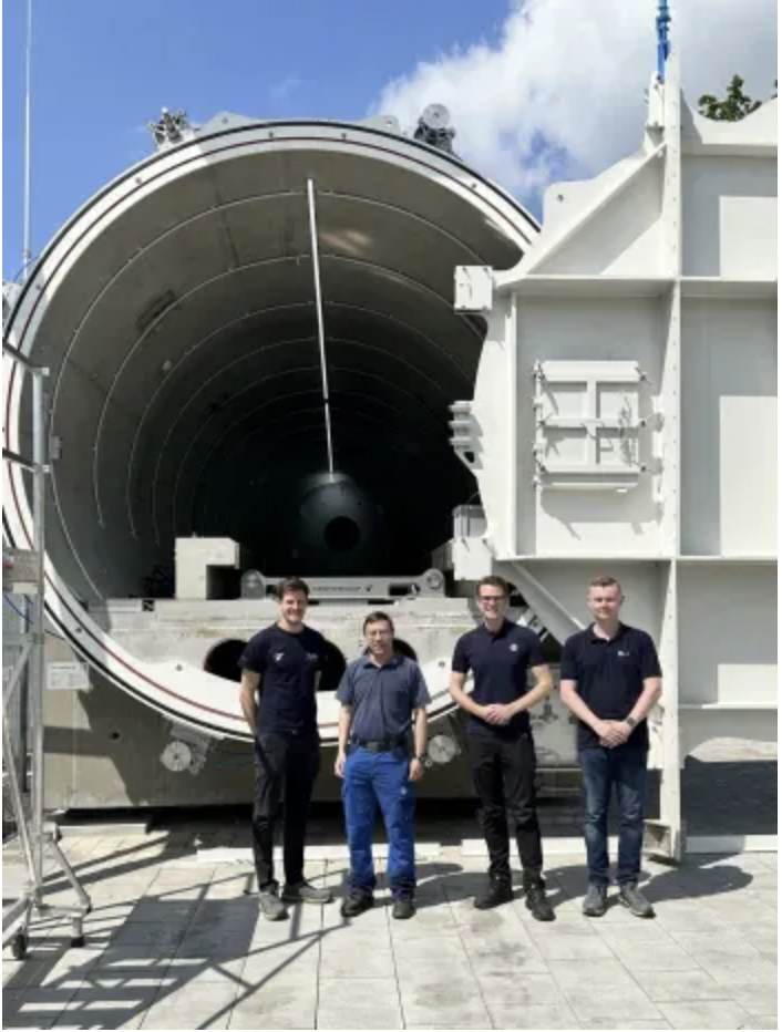 An image of the TÜV SÜD team stood infront of their hyperloop system
