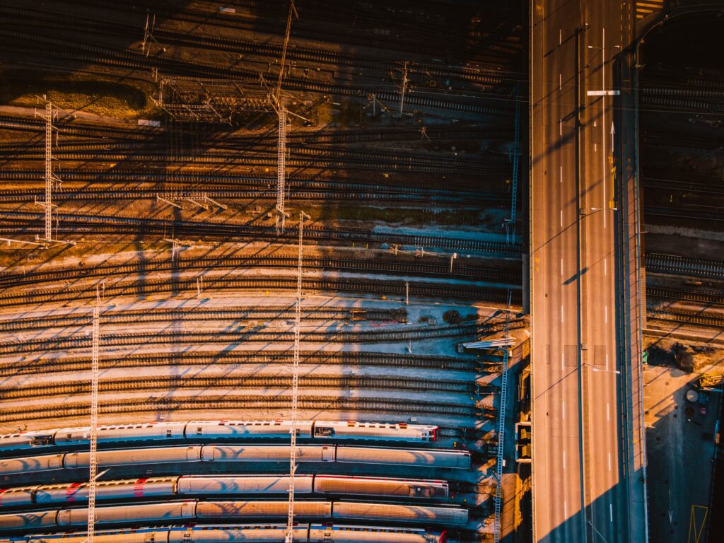 an aerial view of trains on tracks with a road running overhead