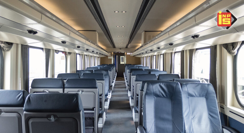 An interior shot of a train, showing the aisle, windows and blue seats