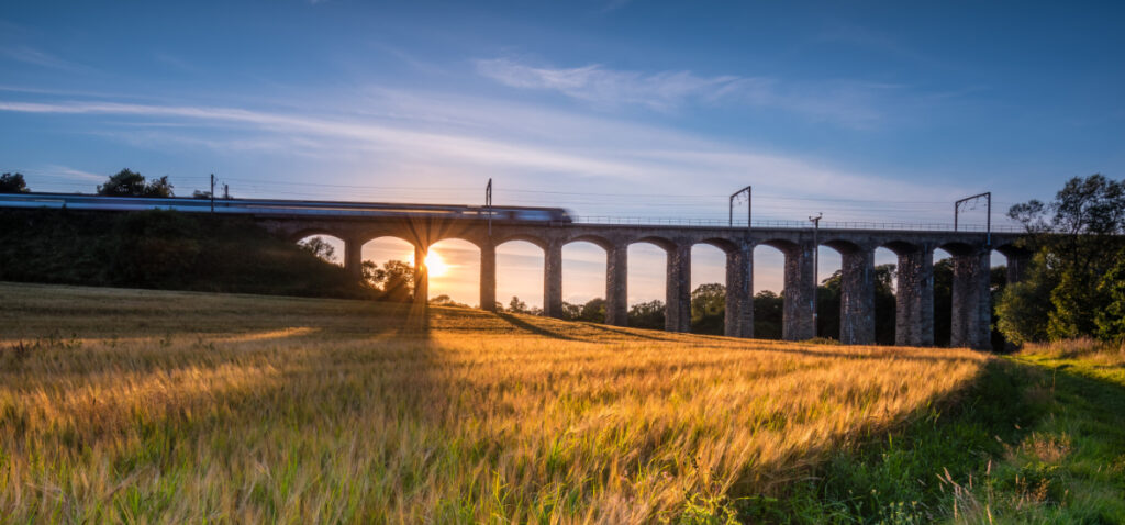 A train travelling over a viaduct at sunrise