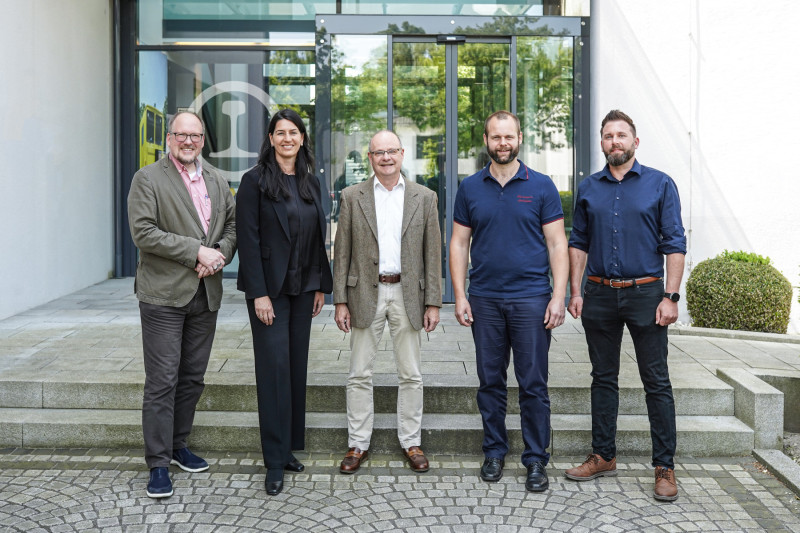 An image of five people standing outside a building