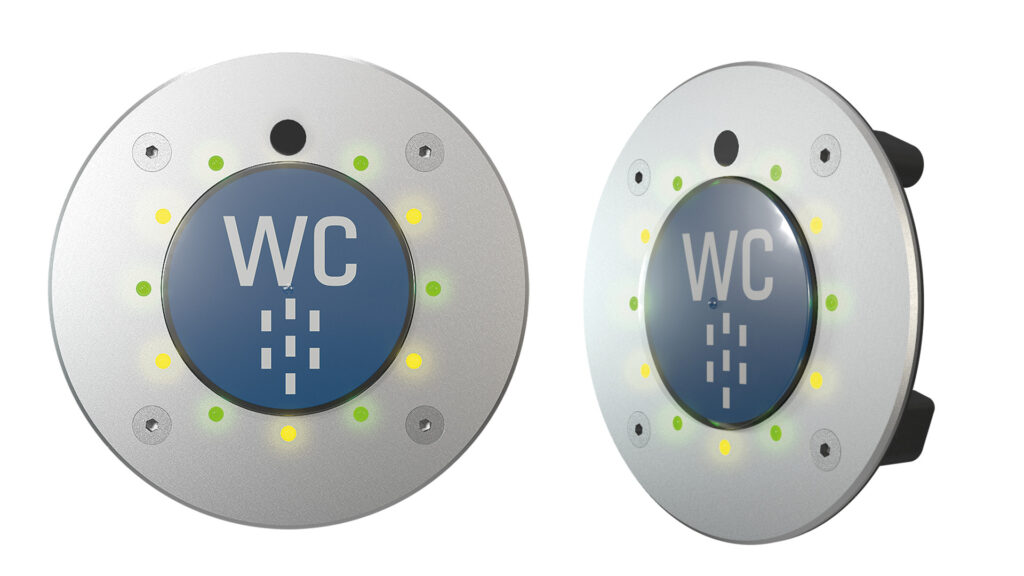 An image of two WC buttons from TSL-ESCHA. Both are silver with a blue disc in the middle, and one is a side profile of the product