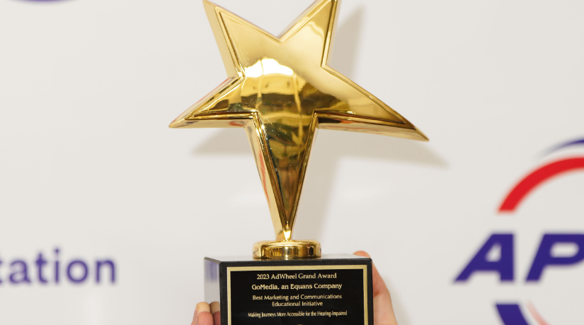 A golden star award. The base reads "2023 AdWheel Grand Award, Go Media, an Equans Company. Making Journeys More Accessible for the Hearing-Impaired