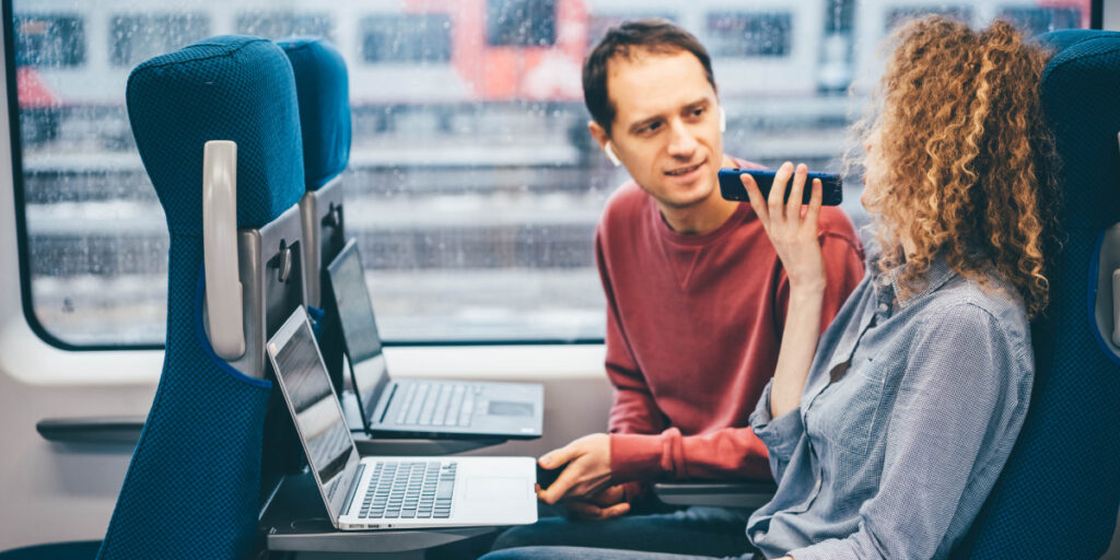 Passengers using their laptops and phones on the train