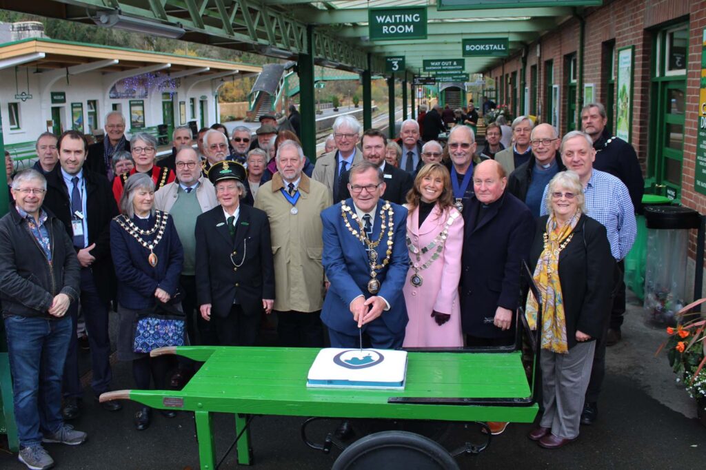 A group of people surround a cake on a green platform