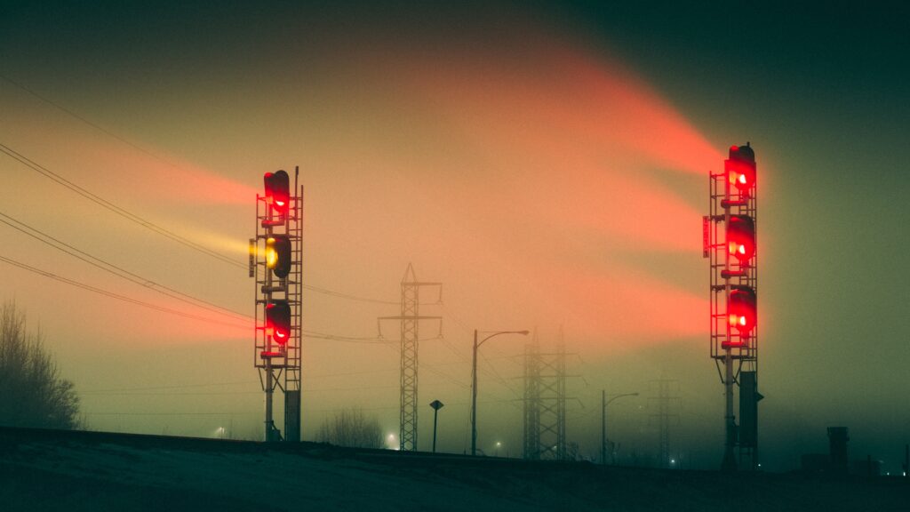 A pair of signalling towers in a dark environment showing red and yellow lights