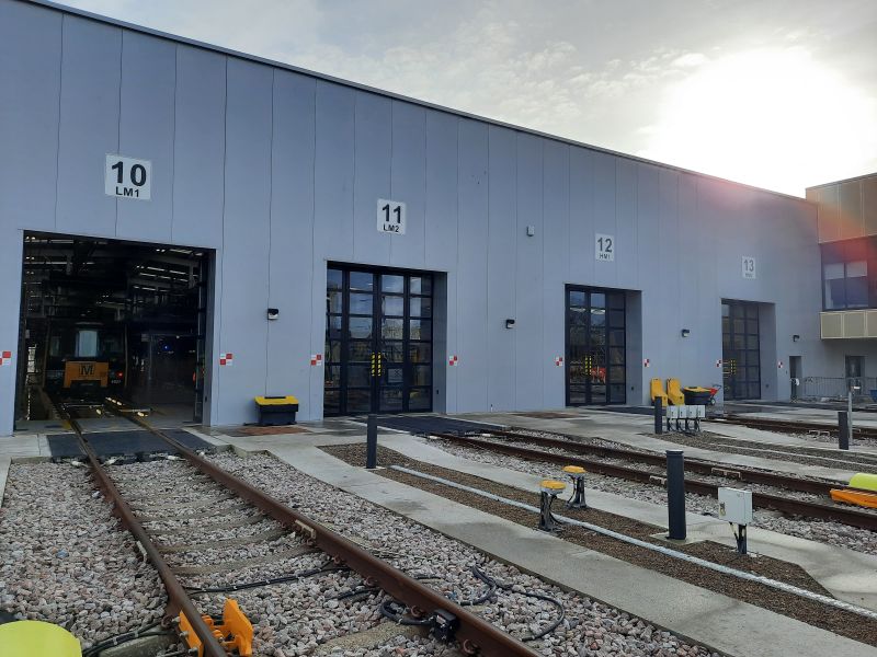 A grey depot building with large folding doors