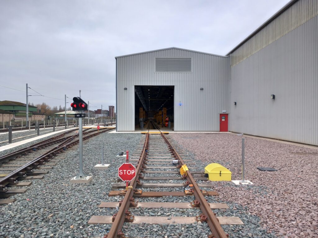 A track leads into a depot building. Attached to the track is a yellow DPPS system from Zonegreen