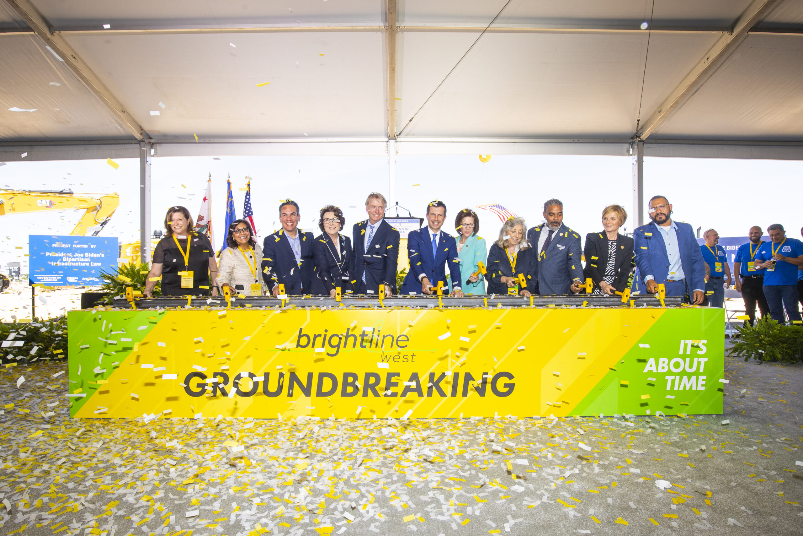 Officials hammer the first spike commemorating the groundbreaking for Brightline West