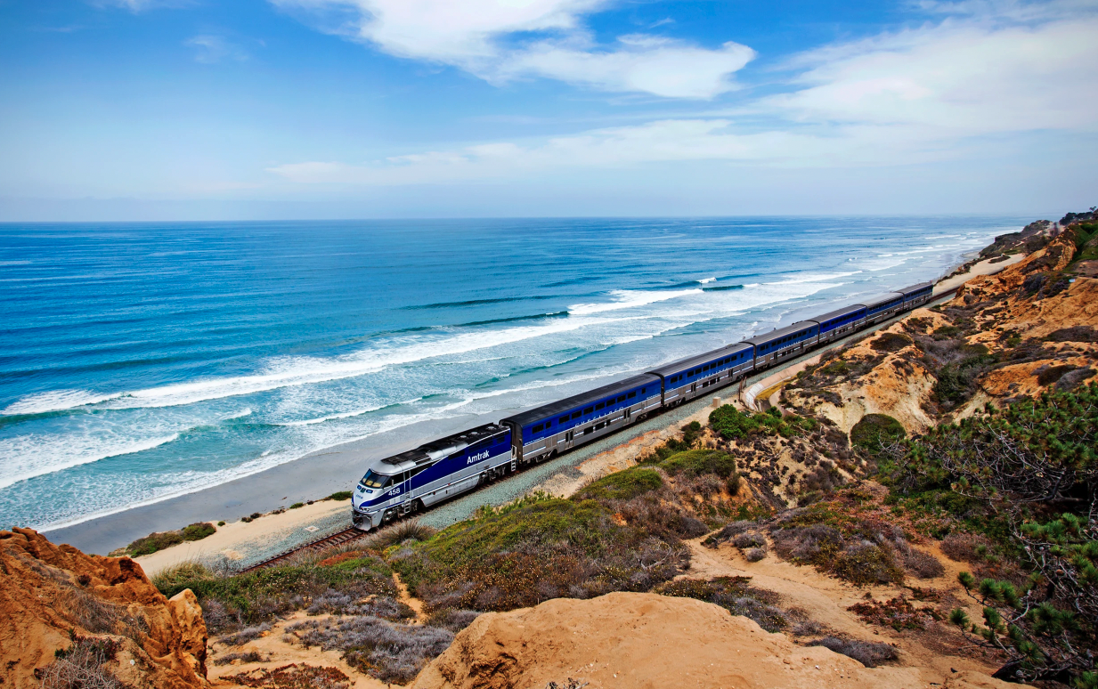 A train travelling along a coastal track beside the sea