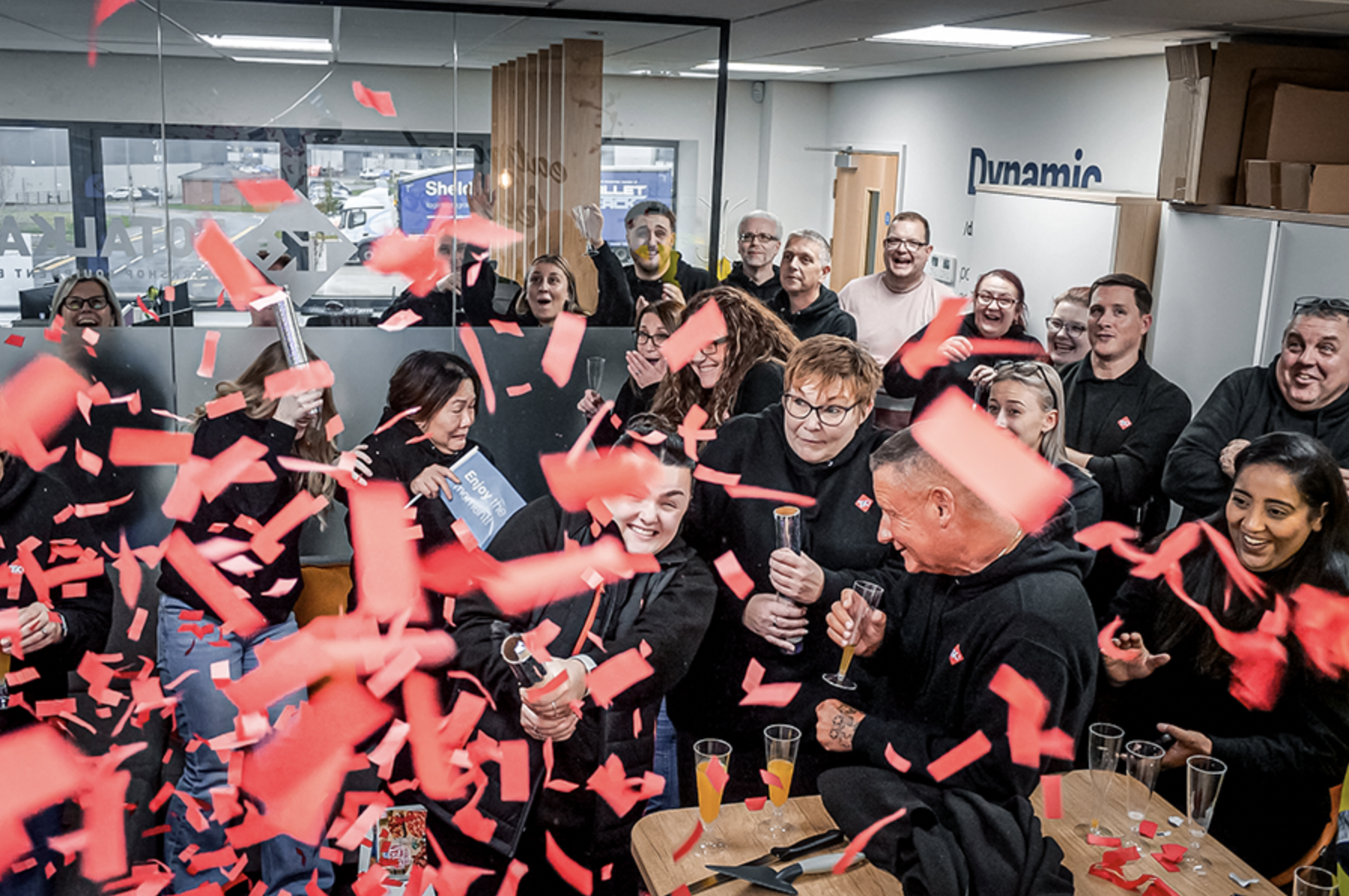 A group of people celebrating, partially obscured by falling red confetti