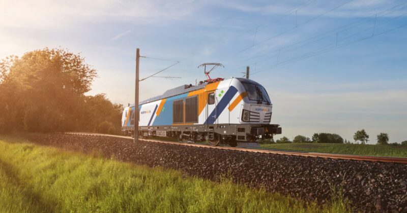 Red German train traveling on railway tracks through nature, near a rural alley, at sunset, near Schwabisch Hall, Germany. Travel concept.