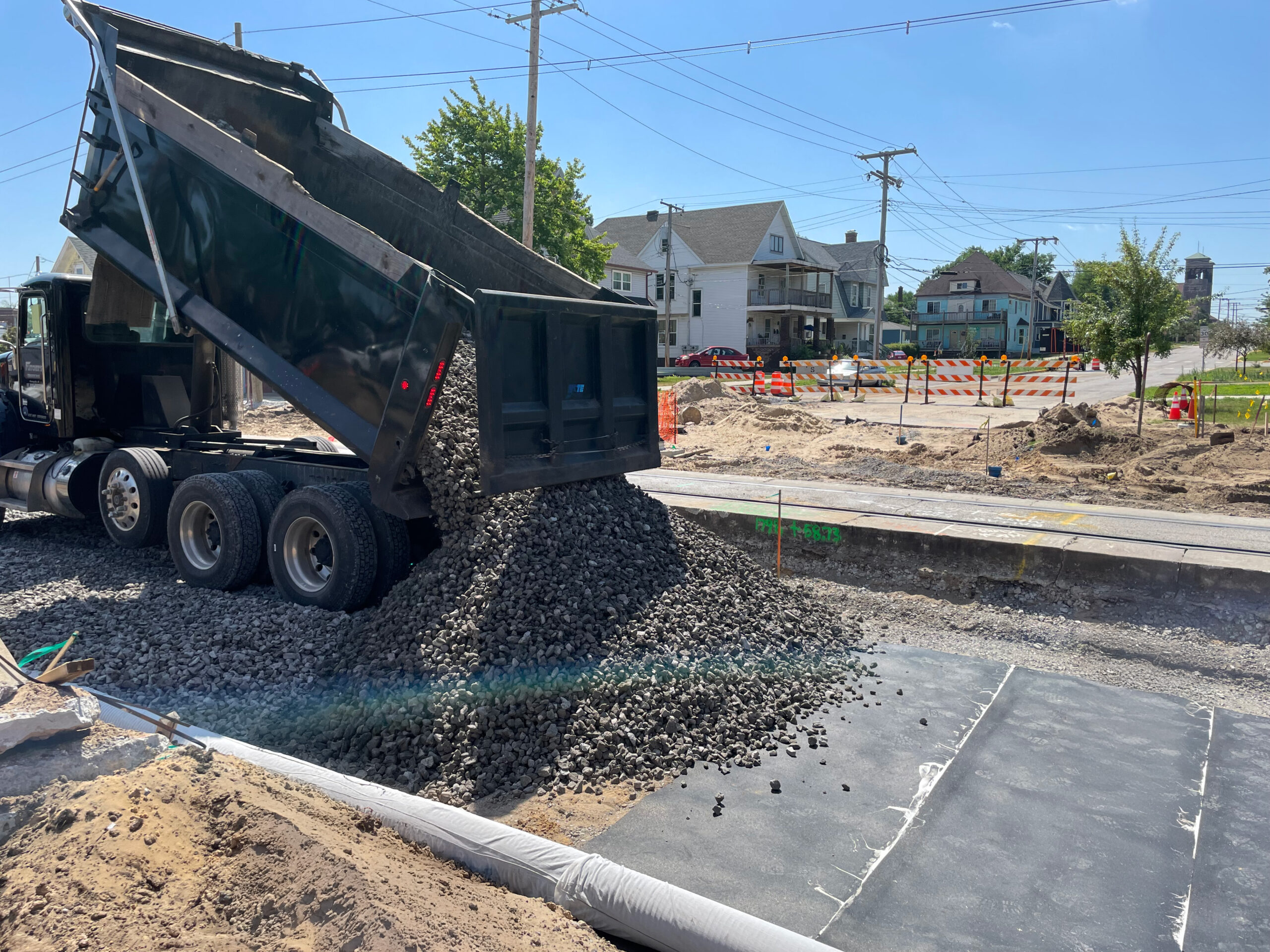 Railway construction site showing rubber underlayment beneath ballast for vibration and noise control.