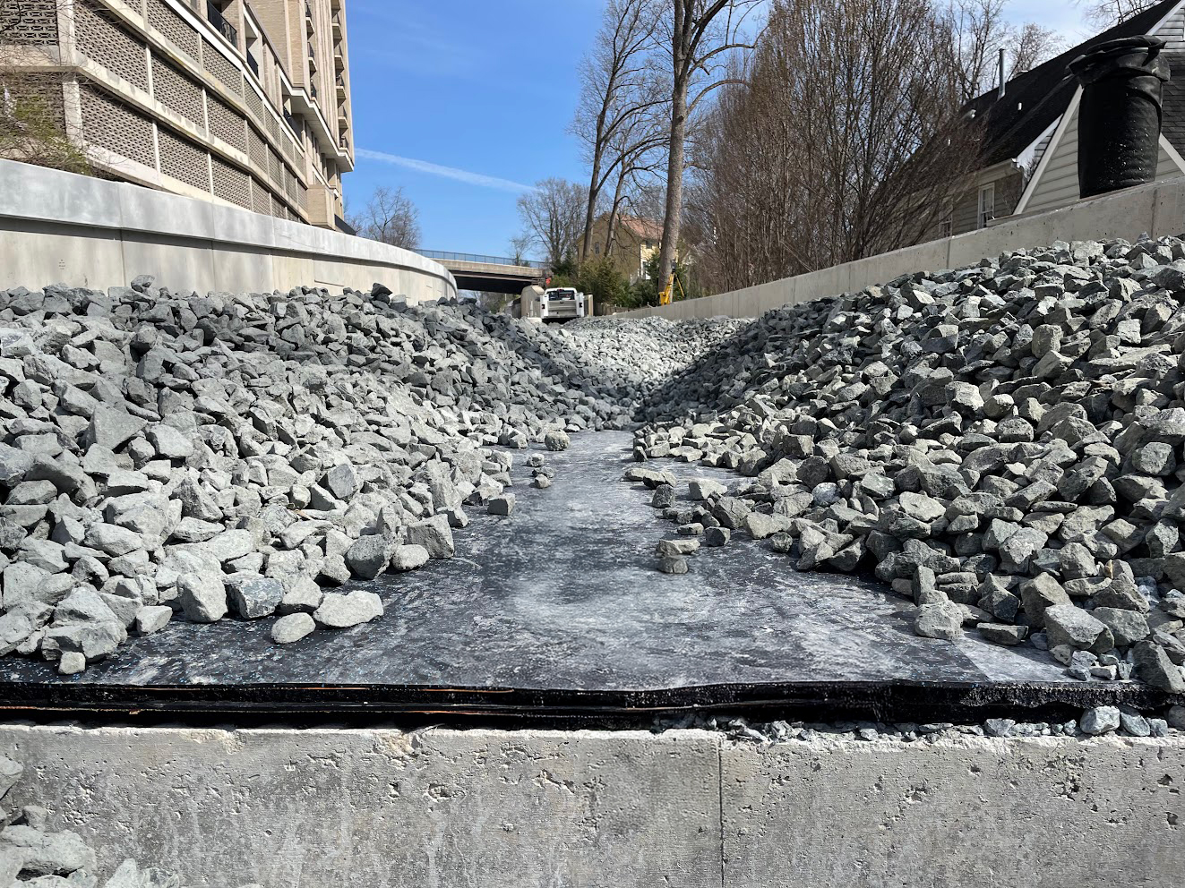 Railway construction site showing rubber underlayment beneath ballast for vibration and noise control.
