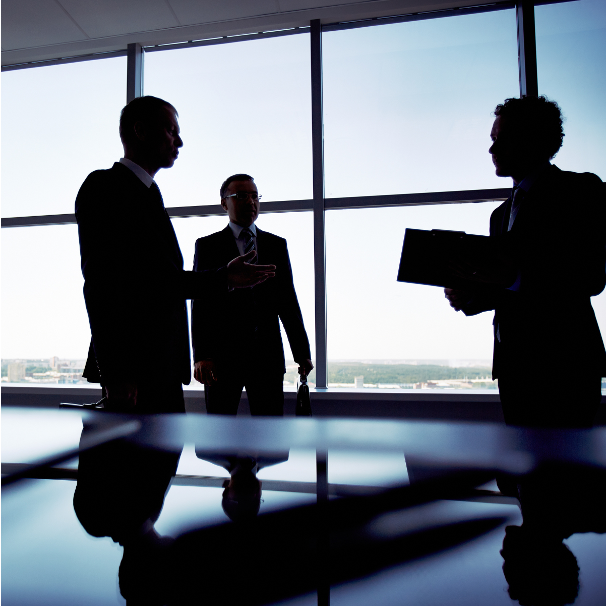 three individuals in a meeting room discussing something