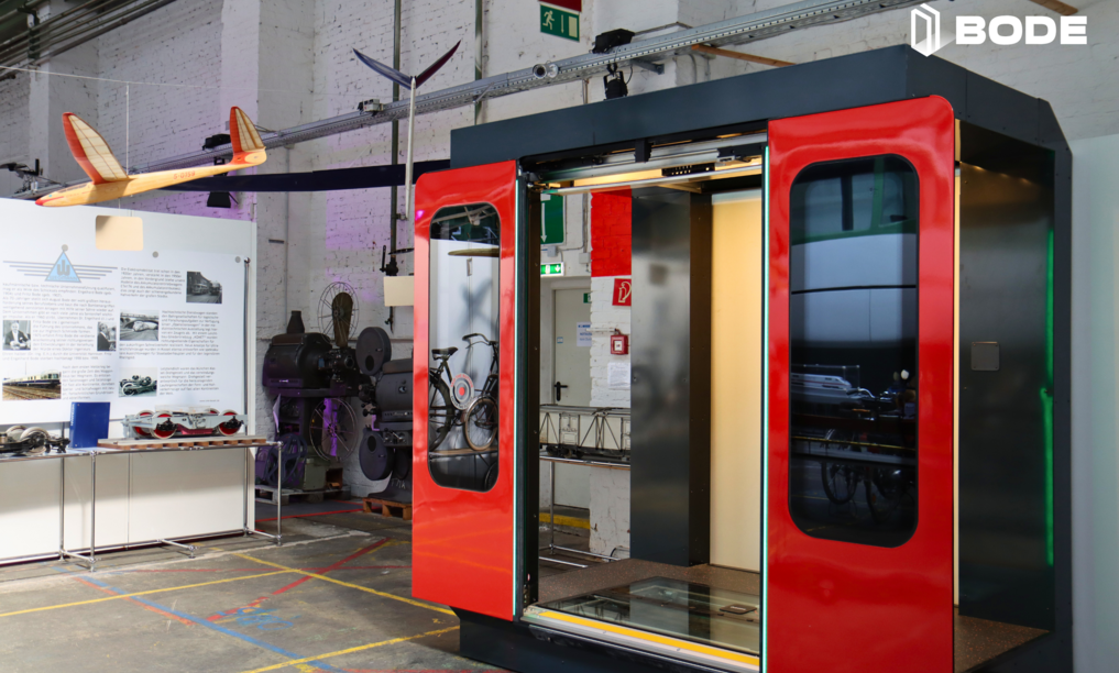 Exhibit at a technology museum featuring a modern train door module by BODE, displayed alongside vintage railway and aviation artifacts.
