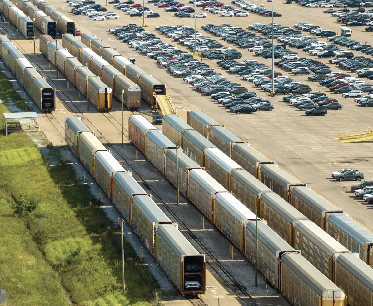 New cars loading on autorack railcars at automotive factory parking lot
