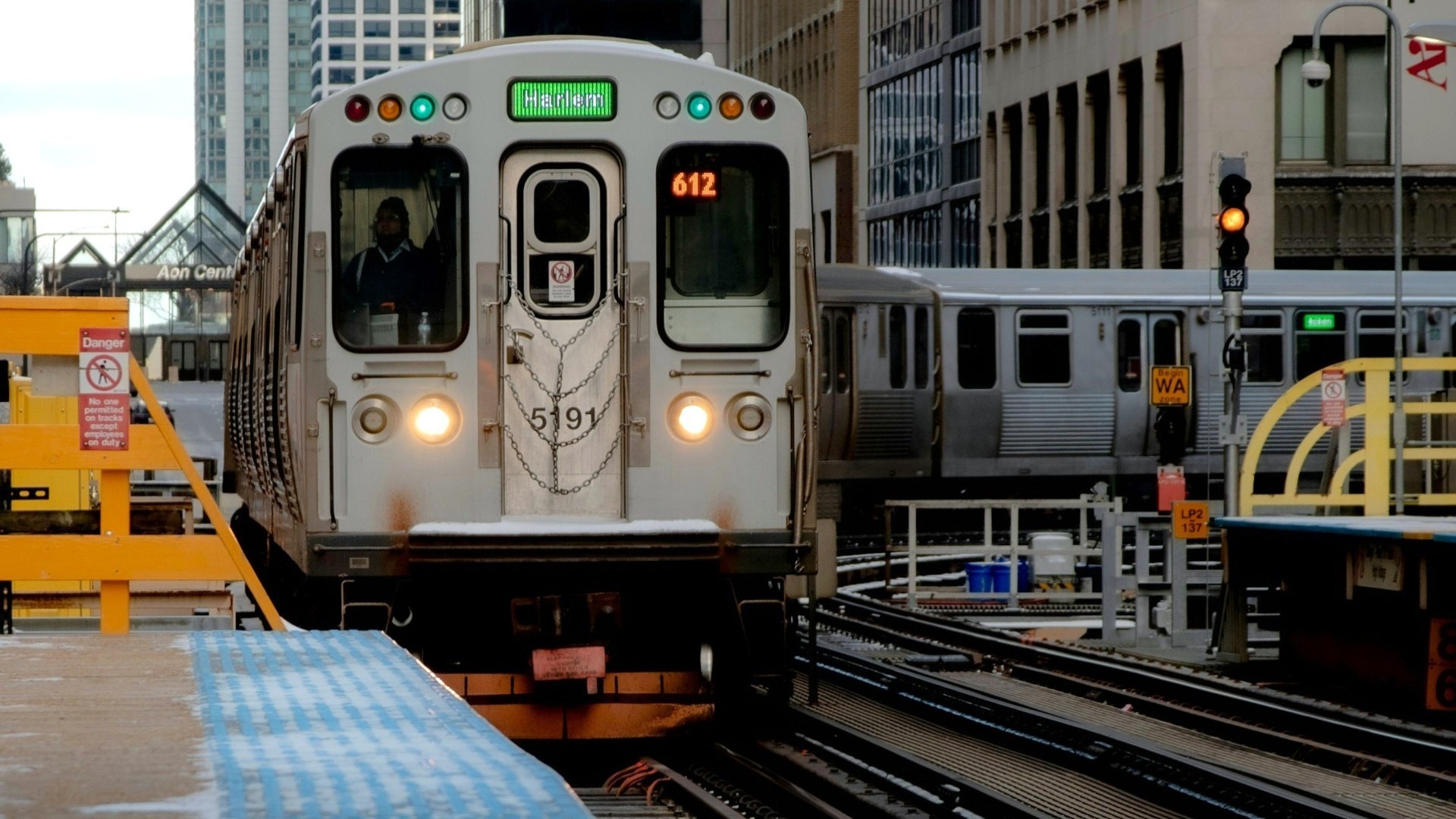 Chicago Transit Authority train approaches a passenger platform after a tight curve. A sign warns of the danger of trespass onto the tracks