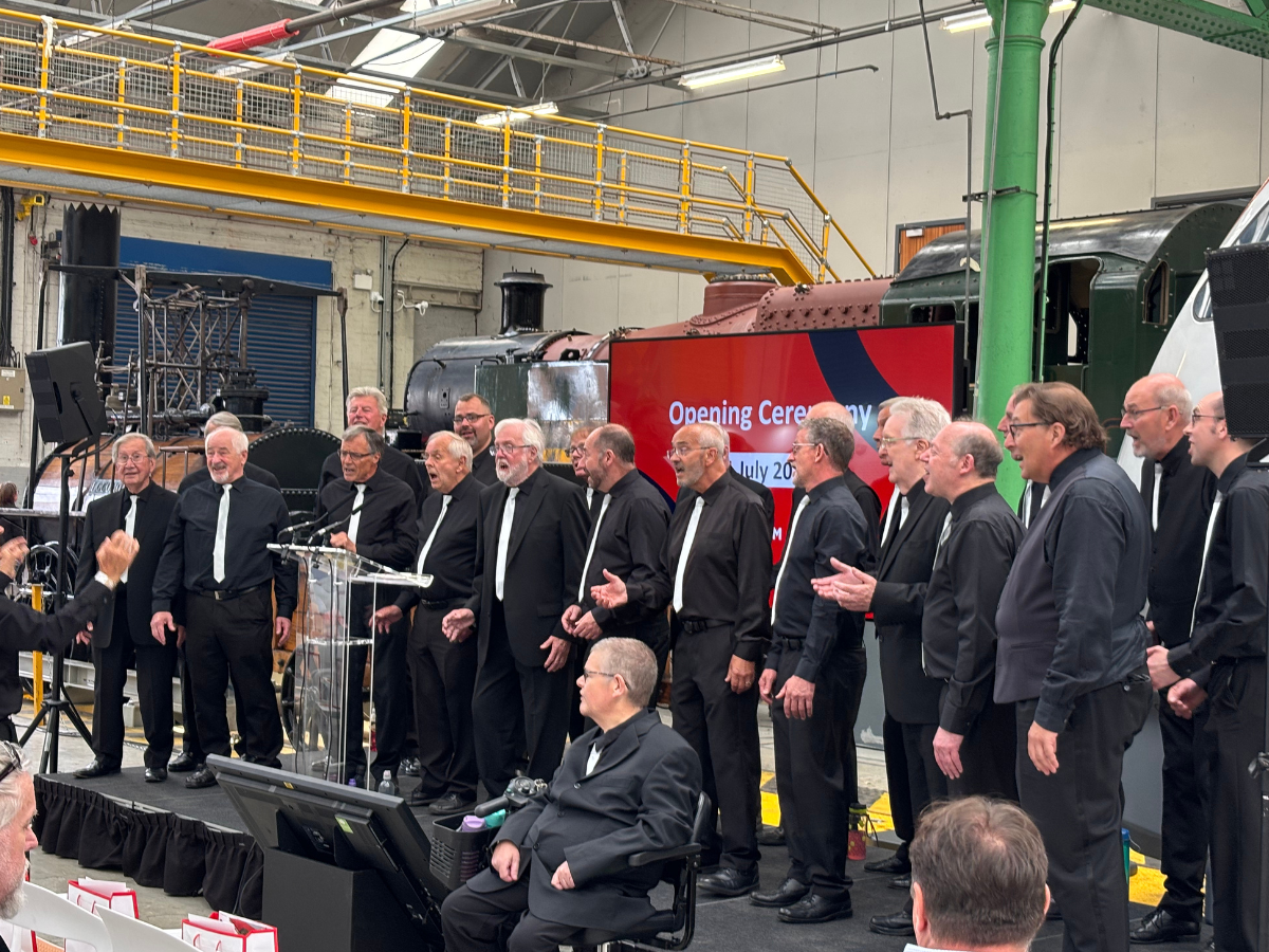 A group of men singing on stage in a factory