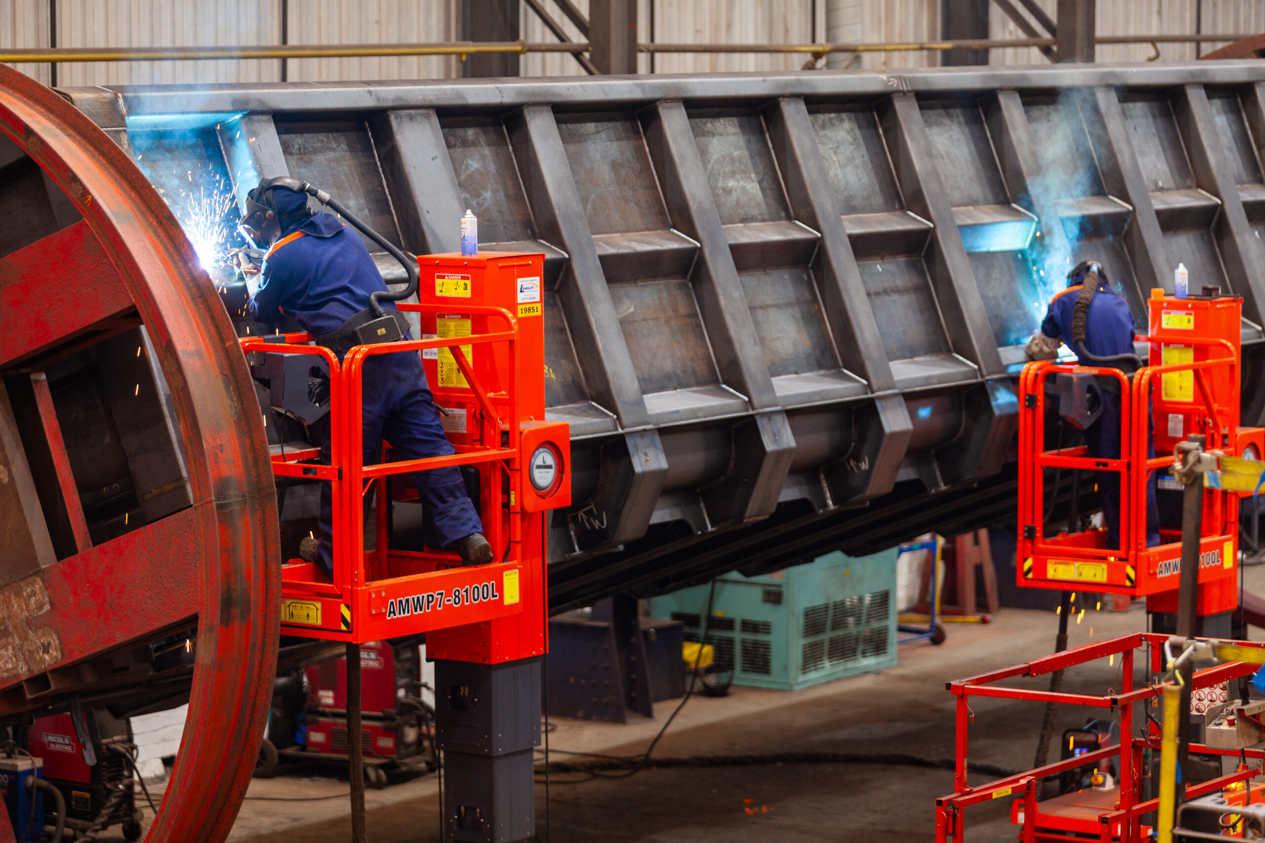 Two workers welding a wagon body whilst on lifts