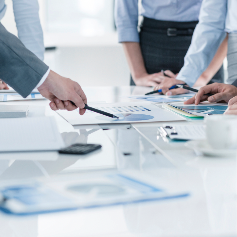 A table in an office, people leaning and pointing at materials