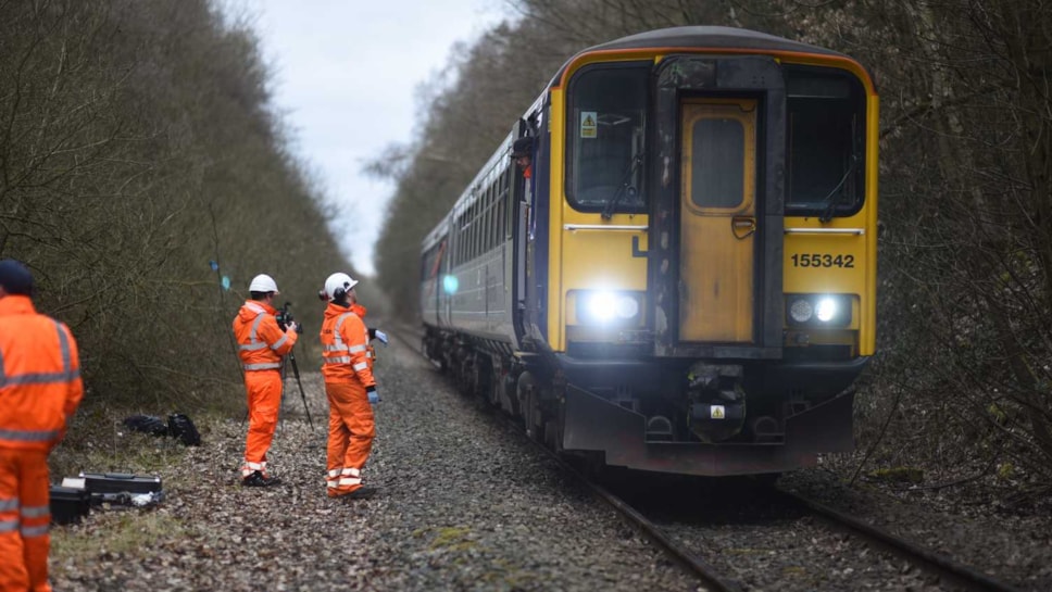 Three rail workers beside a Northern train
