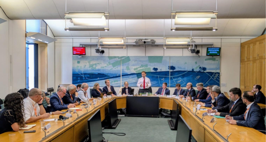 A group of individuals sat around a long table in discussion