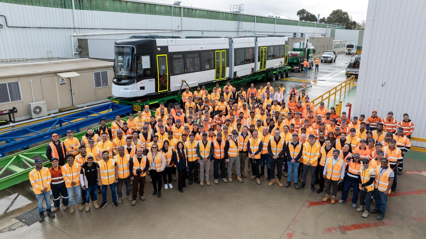 A team of Alstom workers celebrating by a tram
