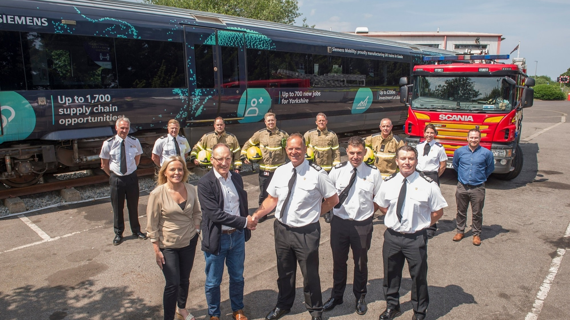 A group of people surrounding a train and a fire engine