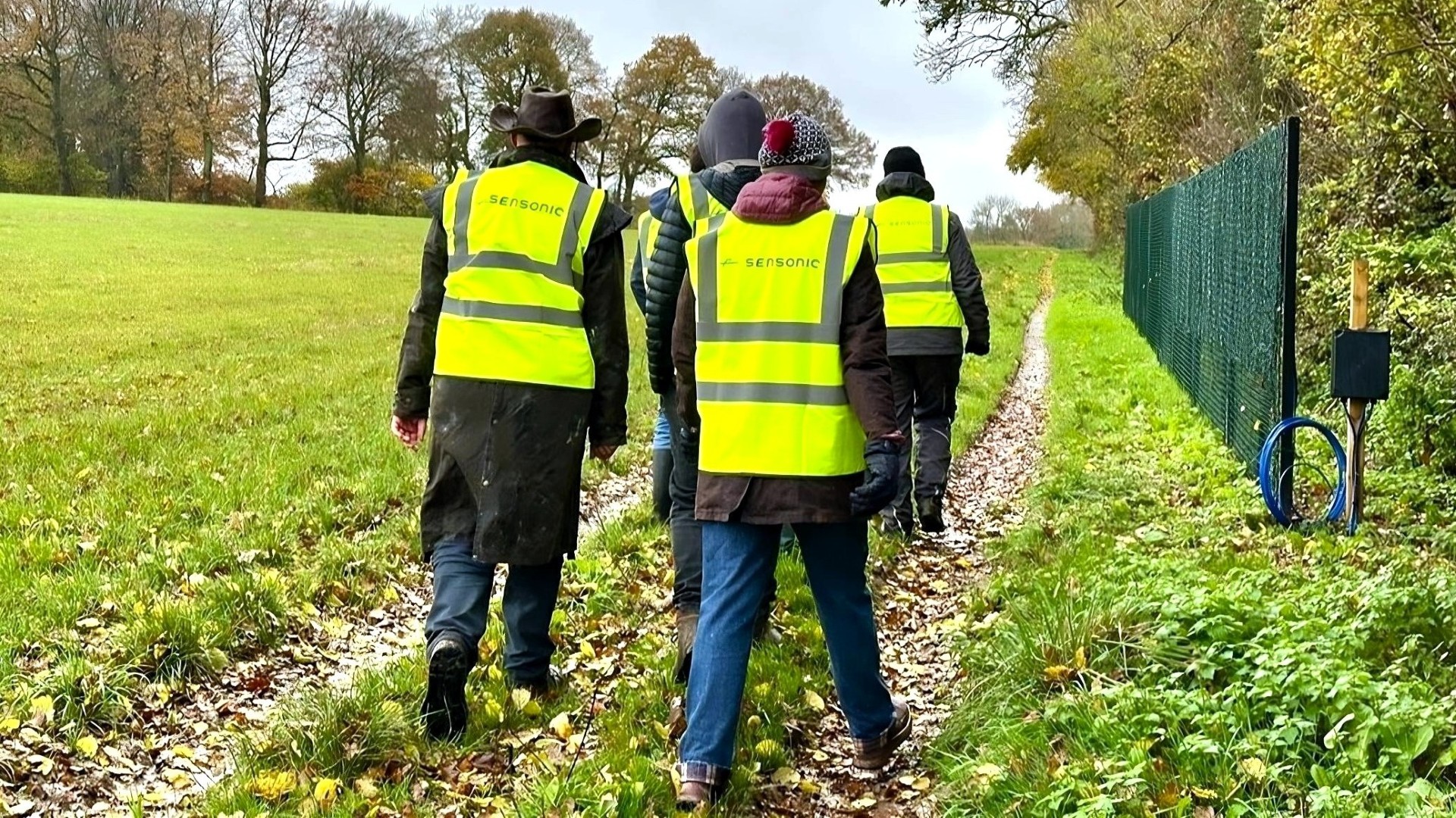 A group of Sensonic workers walking through the countryside, wearing hi-vis yellow vests