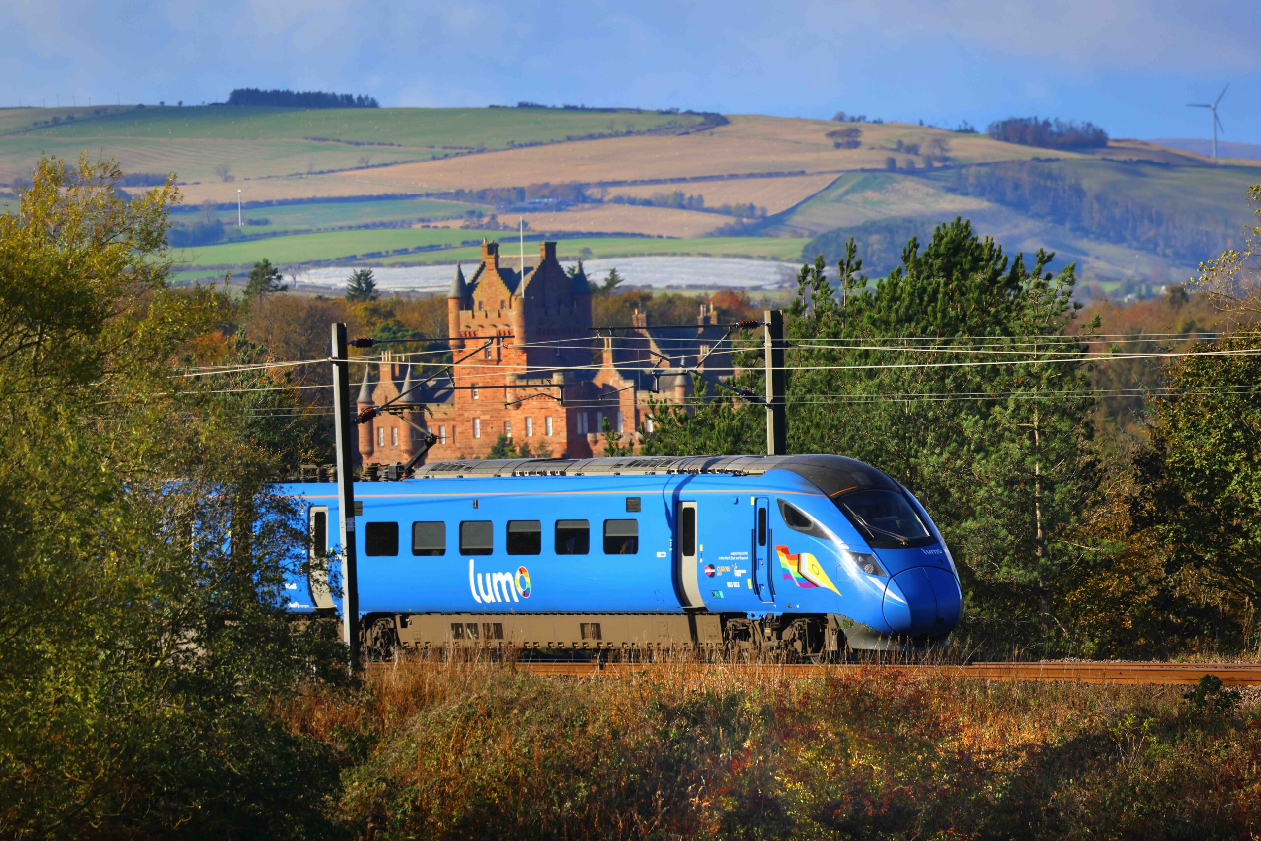 A blue train travelling past a castle