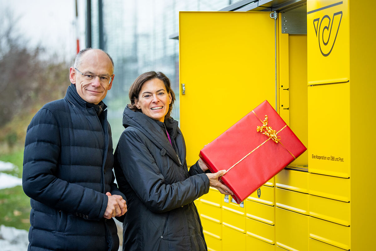 Two people happily putting a present into a big yellow locker 