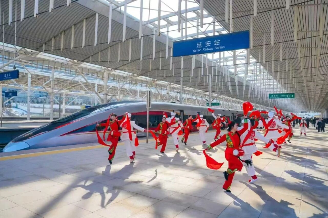 A group of people dancing around a train at a station