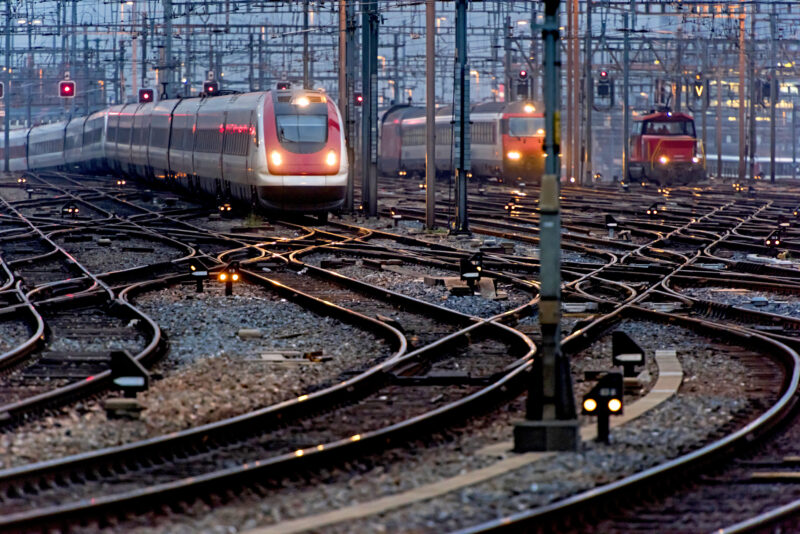 Commuter train approaching busy railway track field at twilight