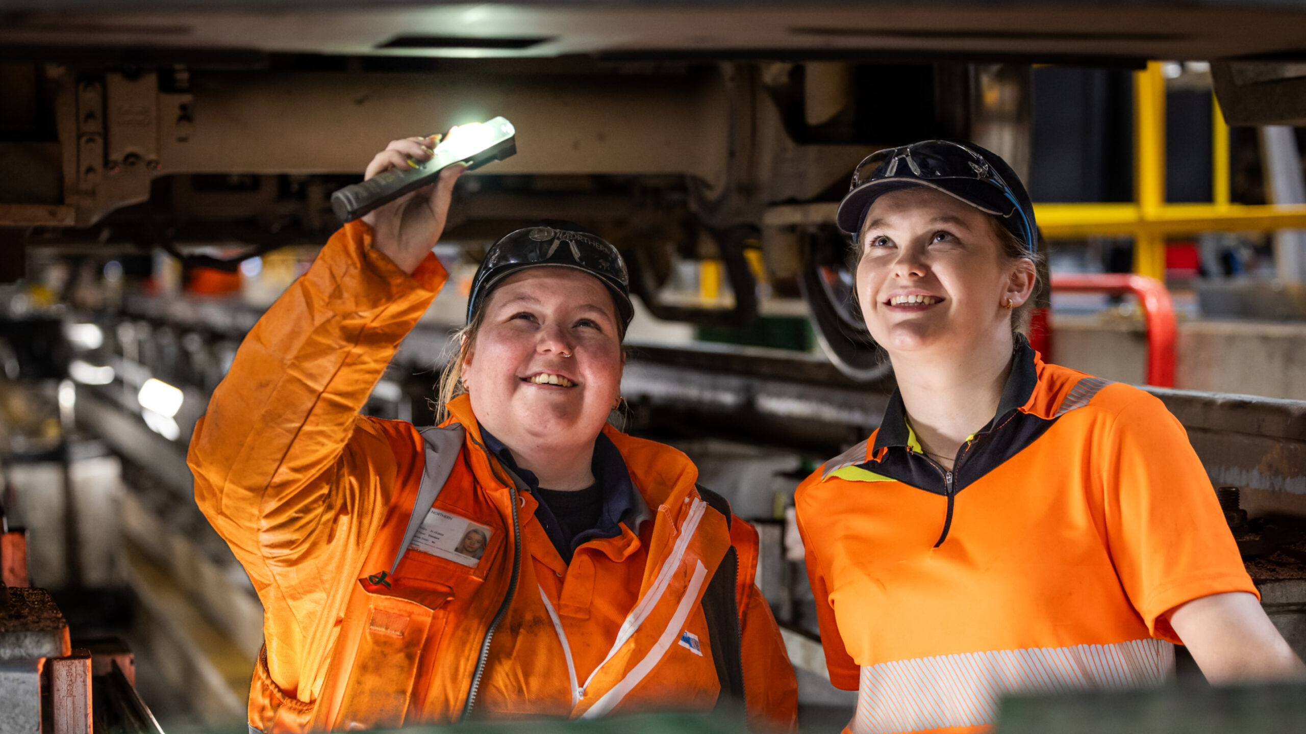 Two young people working underneath a train