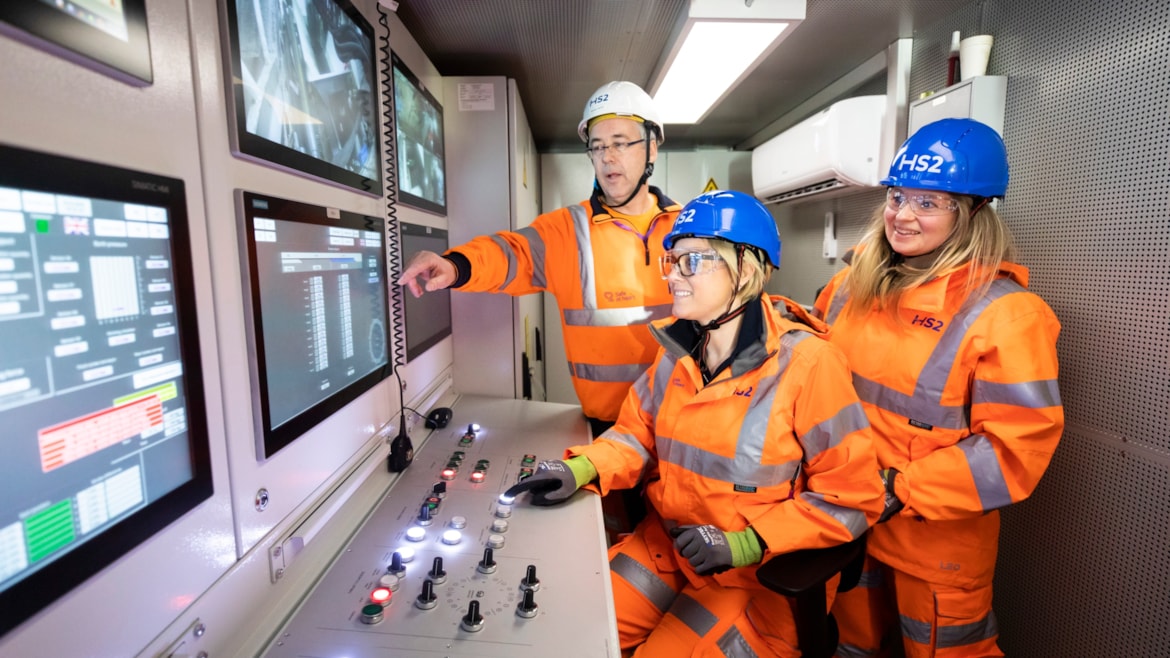 Three people stood in a control booth