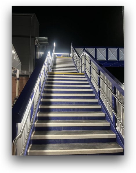Linear LED luminaires integrated into the stair structure of the Dumfries Station passenger footbridge provide uniform illumination while maintaining a clean architectural appearance.
