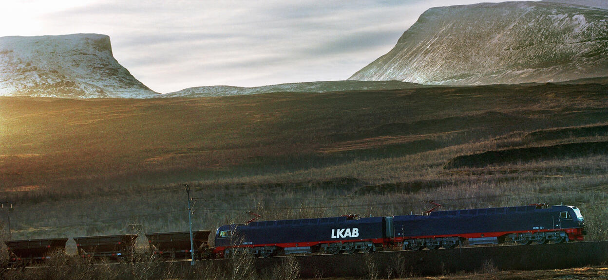 LKAB Malmtrafik AB freight train with locomotives on track, and Lapporten in background, Kiruna