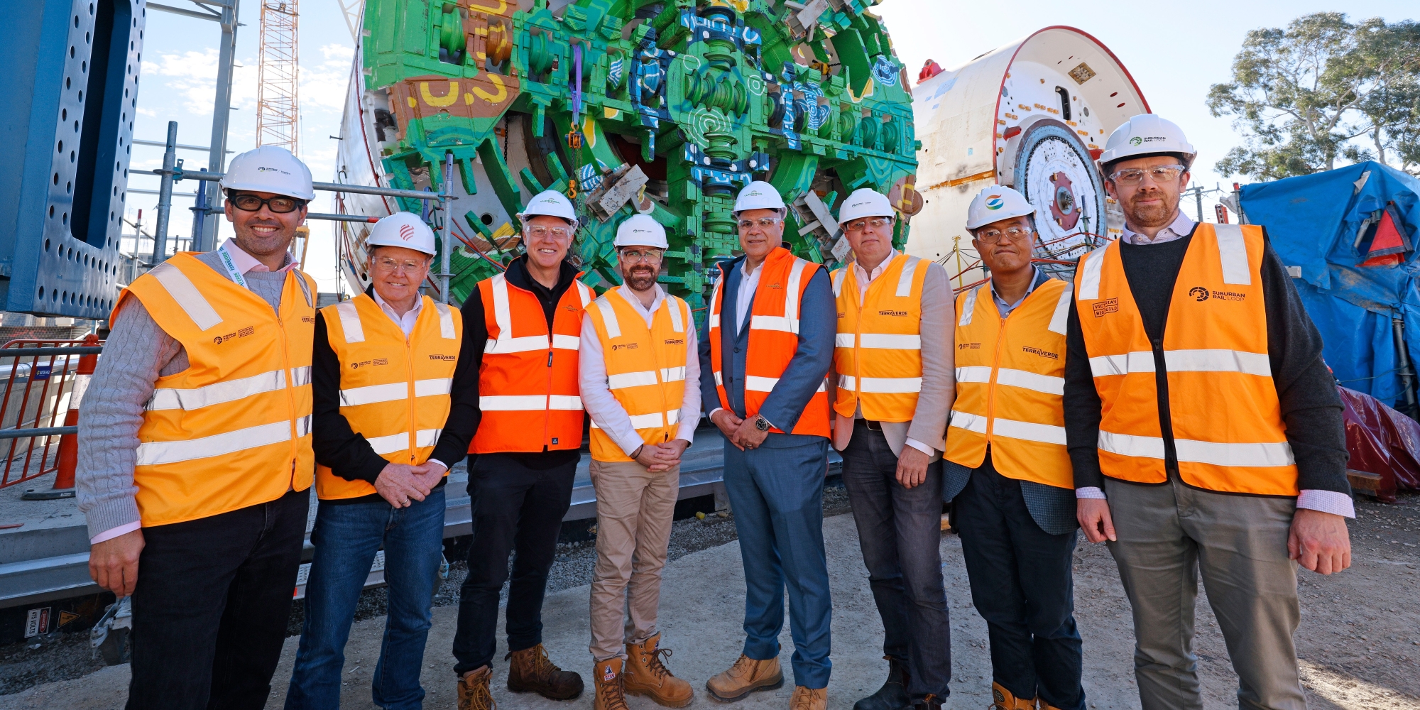 A group of people stood in front of a tunnel boring machine