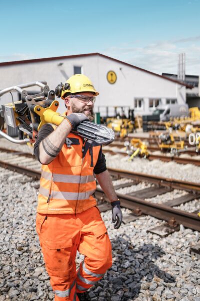 Construction worker carrying a tamping machine